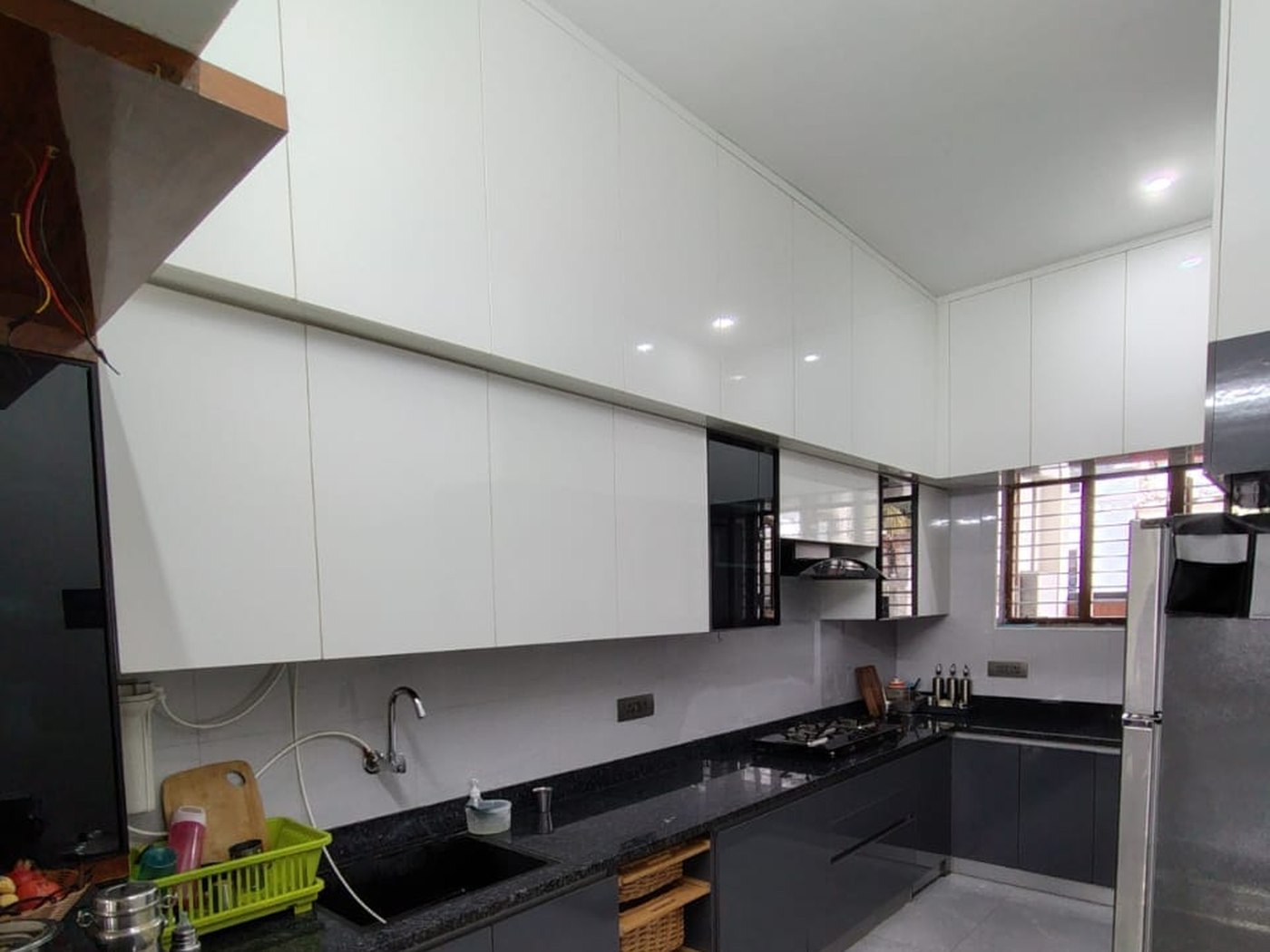 Modular kitchen in graphite and white with a stone counter and tall units, by Padmodya Interiors