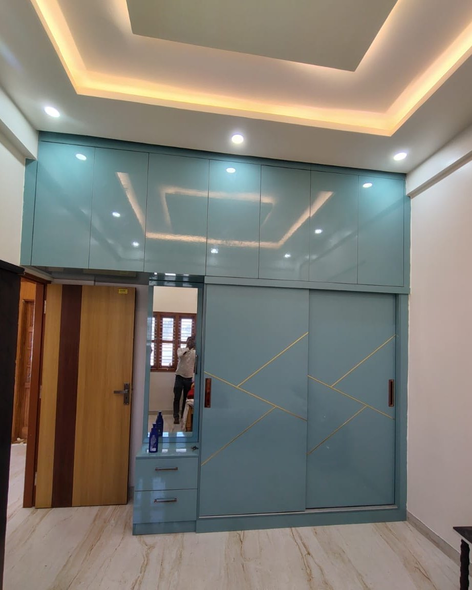 Sliding wardrobe in teal lacquer with brass inlay and a recessed ceiling, by Padmodya Interiors