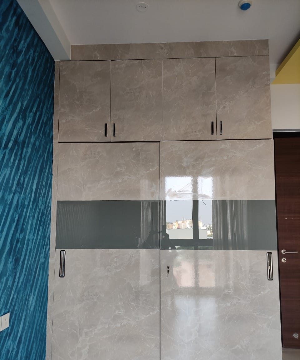 Stone-finish wardrobe with glass banding, by Padmodya Interiors